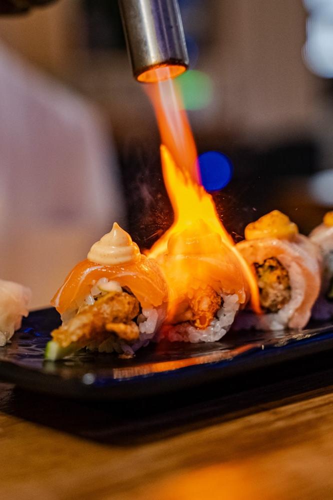 fotografía gastronómica piezas de sushi california roll siendo flambeado espectaculo gastronomico