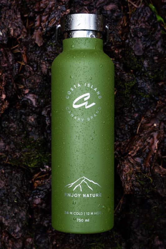 fotografía de producto botella verde de canary brand sobre fondo de tierra