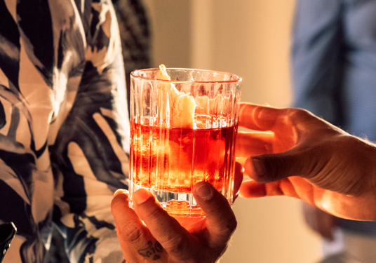 fotografía gastronómica personas compartiendo un vaso con una bebida alcoholica
