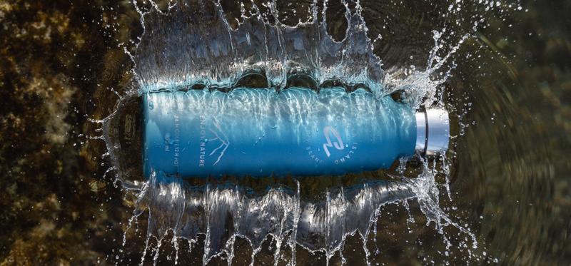 fotografía de producto botella azul de canary brand cayendo al agua